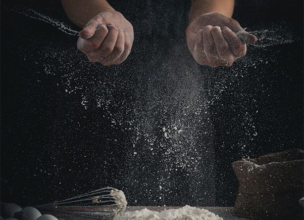 Image of a chef tossing some flour onto a surface with eggs and whisk to support open chicken sandwich article