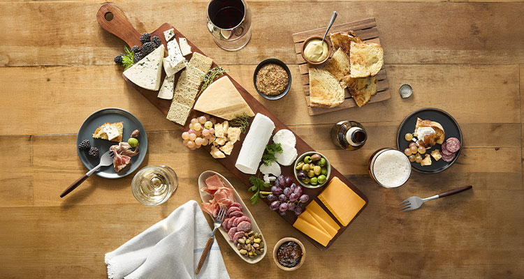 wooden table with a selection of cheeses & meats