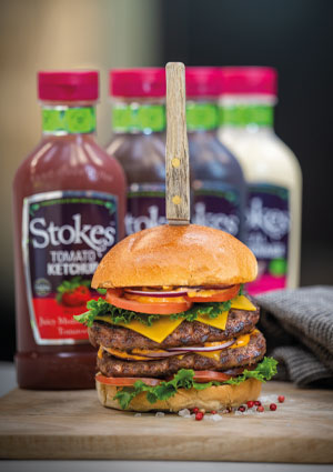 Burger stack in front of sauce bottles
