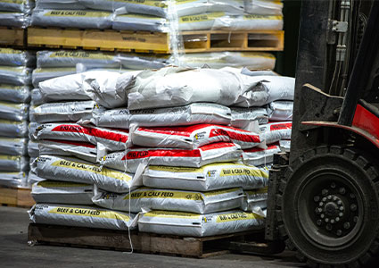 sacks of animal feed on a pallet being moved by a forklift