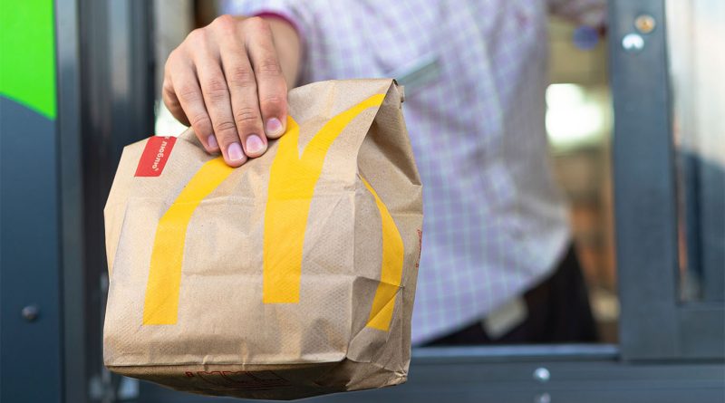 Mcdonald's bag being handed to customer out of drive-thru window to support McCrispy Strips and Snack Wrap article