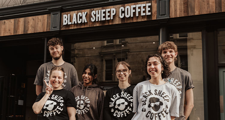 group of employees in front of a Black Sheep Coffee shop