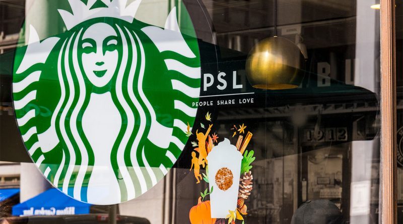 Starbucks PSL returns for 2025 with a refreshed fall menu Window display at a Starbucks store featuring the Pumpkin Spice Latte (PSL) promotion with fall-themed illustrations including pumpkins, leaves, and cinnamon sticks, alongside the Starbucks logo.