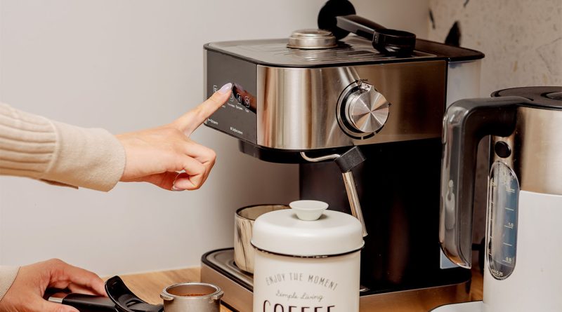 Top 5 Best Coffee Machines in the US for 2025 A person using a modern espresso machine on a kitchen counter, with a coffee canister, portafilter, and electric kettle nearby to support best coffee makers 2025 article