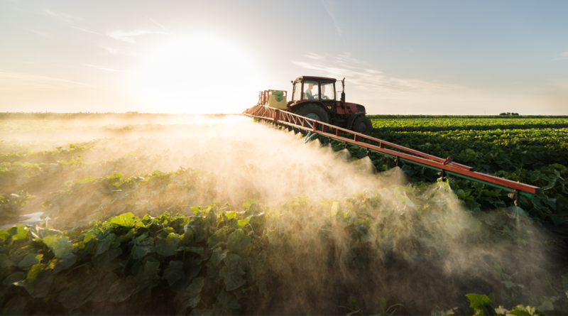 Farmer on a tractor with a sprayer makes fertilizer