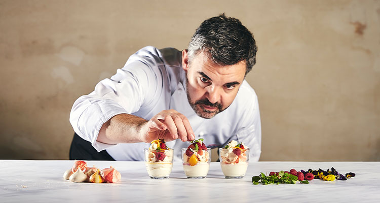 a professional chef meticulously plating individual desserts in small glasses