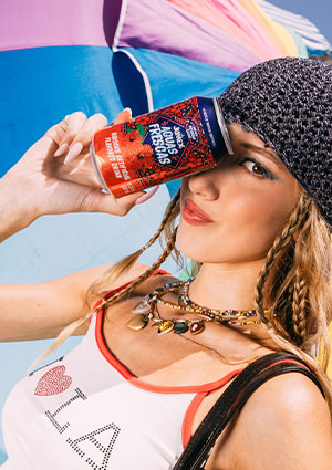 a person playfully posing with a beverage in a bright, outdoor setting.