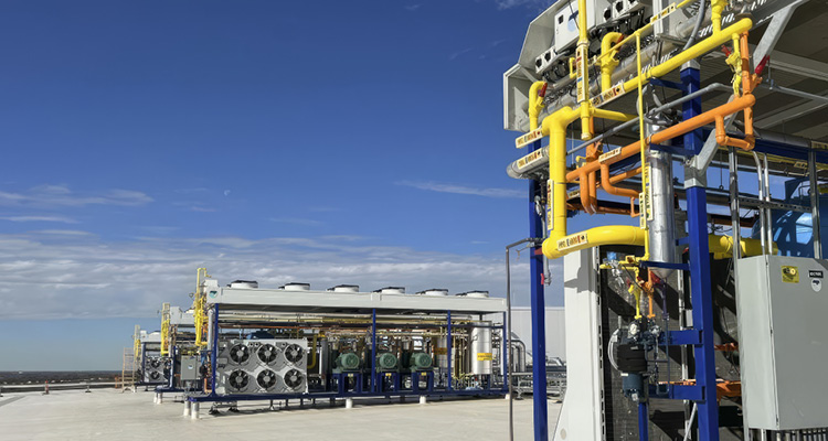 a modern industrial gas processing or hydrogen demonstration plant set against a clear blue sky