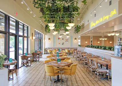  Pür & Simple restaurant location featuring yellow chairs, wooden tables, and hanging plants