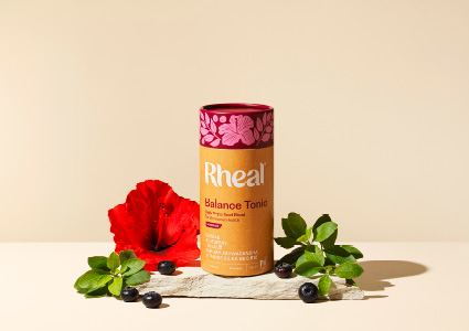 a Rheal Superfoods Balance Tonic container in a vibrant pink and orange color