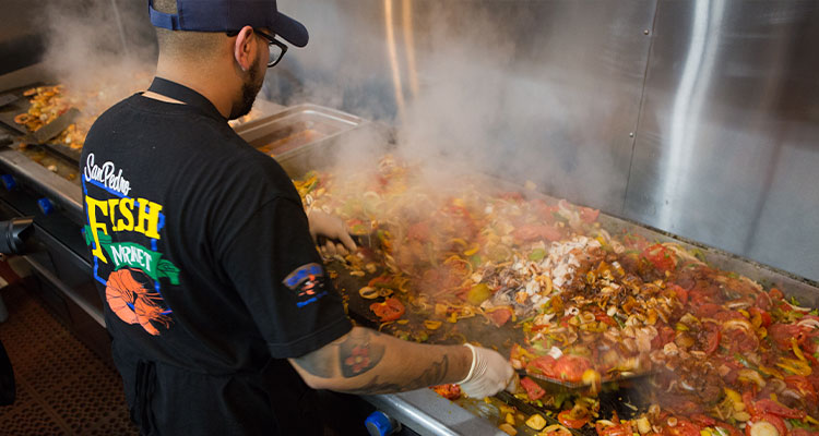 a cook preparing a large seafood dish at the San Pedro Fish Market