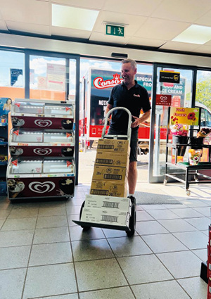 a person using a foldable metal sack truck to transport boxes