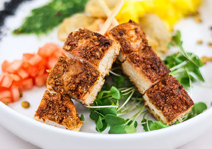 a close-up, top-down view of an appetizing plated dish, prominently showcasing skewered pieces of seasoned and seared meat