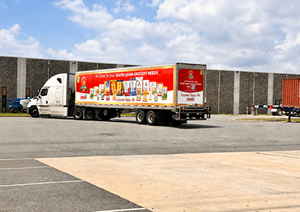 a tractor-trailer features a prominent red wrap advertising South Asian grocery products