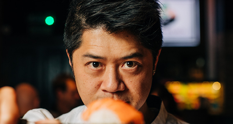 Teddy Lee, the founder and CEO of the Japanese restaurant chain Maki & Ramen, holding a piece of sushi