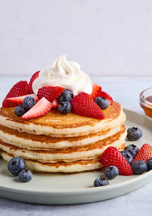 a tall stack of golden-brown, fluffy American-style pancakes