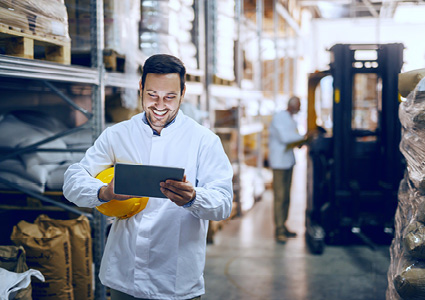 a person in a warehouse setting using a digital tablet