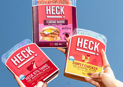 three HECK! Food meat product packages being held up against a blue backdrop