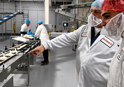 DeIorio Foods team members inspecting frozen dough products on a production line at the company’s manufacturing facility.