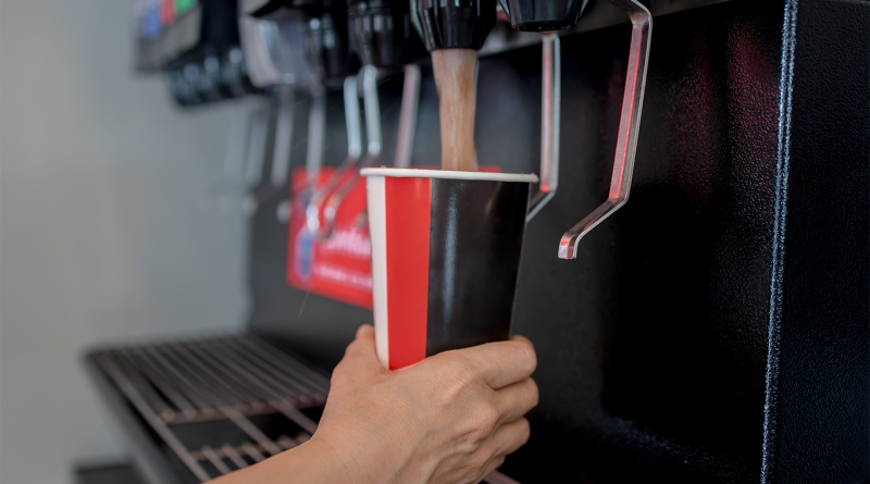 Close-up of a hand squeezing a soda from a vending machine
