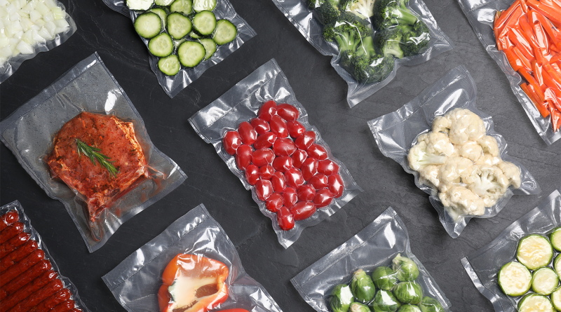 Flat lay composition of different food in vacuum packings on dark grey table