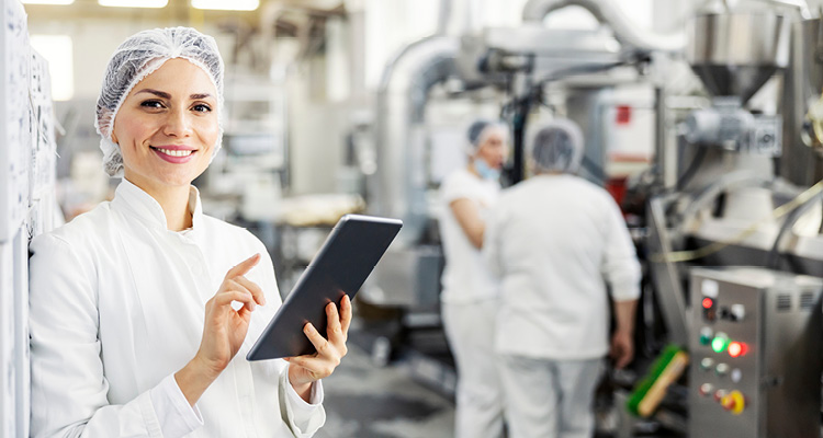 a smiling food production supervisor wearing a hairnet and white lab coat