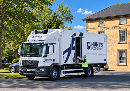white delivery truck branded with the logo for "Hunt's Food Group" parked outdoors on an asphalt surface