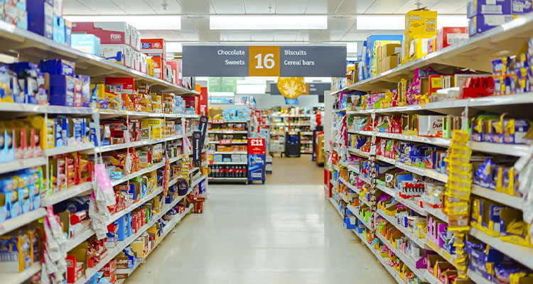a supermarket aisle lined with shelves stocked with packaged snacks, chocolate, biscuits, and sweets