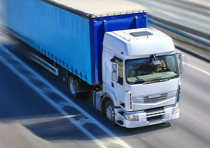 a white articulated tractor unit pulling a blue curtain-sider semi-trailer truck on a highway