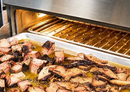 slow-smoked beef brisket slices and cubed burnt ends resting in a metal tray with savory pan juices